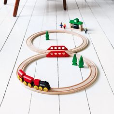 a toy train set sitting on top of a white floor next to a wooden chair