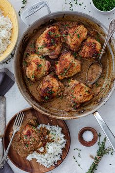 a pan filled with meat and rice on top of a white table next to silverware