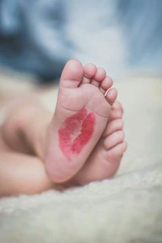 a baby's foot with a red lip stain on the top of its toe