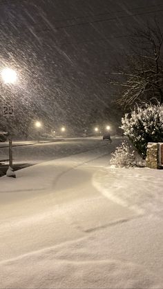 a snow covered street at night with cars driving on it