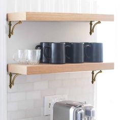 two wooden shelves with coffee mugs and a toaster on them in a kitchen