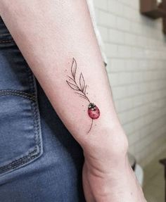 a ladybug tattoo on the left arm with a leaf and flower in it