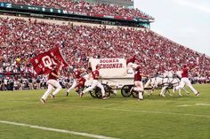 a group of men riding on the back of horses pulling a wagon down a field