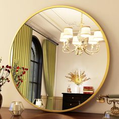 a round mirror sitting on top of a wooden table next to a vase filled with flowers