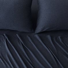 a bed with blue sheets and pillows on it