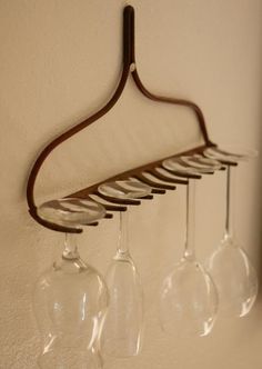 three wine glasses hanging on a wall with a wooden hanger holding four wine glasses