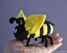 a hand holding a yellow and black stuffed animal