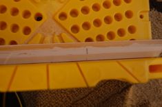 a yellow plastic object with holes in the middle on carpeted area next to wall