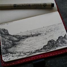 a pen is sitting on top of an open notebook with a landscape drawn on it