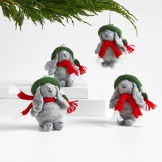 three small stuffed animals are hanging from a christmas tree branch with red and green scarfs