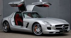 a mercedes sls roadster with its doors open and the door opened, parked in front of a building