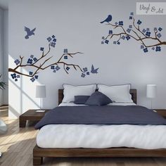 a bed room with a neatly made bed and two birds on the tree branch wall decals