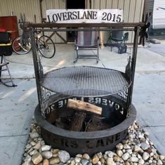 an outdoor fire pit sitting on top of a gravel covered ground next to a building