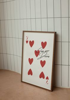 a playing card with hearts on it sitting in front of a tiled wall and floor