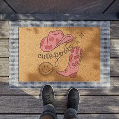 a person standing in front of a cute boot door mat on a wooden deck with their feet up