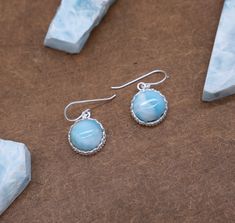 Discover elegance and grace with our Round Larimar Stone Dangle Earrings. Each earring features a captivating circle Larimar stone at the center, delicately framed by intricate filigree-style silver flowers. These stunning earrings boast a diameter of 1.3 cm and a total weight of 6.7 grams, combining sophistication with delicate craftsmanship. Features: Circle Larimar Stones: Each dangle earring showcases a mesmerizing circle Larimar stone, renowned for its serene blue hues and association with the calming energy of the sea. Filigree Silver Flowers: Delicate and intricate filigree-style silver flowers encase the Larimar stones, adding an elegant touch to these captivating earrings. Elegant Dimensions: With a diameter of 1.3 cm, these earrings strike the perfect balance between subtle sophi Blue Larimar Earrings For Gift, Larimar Dangle Earrings For Gifts, Larimar Earrings, Larimar Jewelry, Stone Dangle Earrings, Larimar Stone, Unique Gemstones, Jewelry For Her, Stunning Earrings