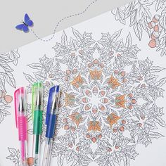 three pens sitting on top of a coloring book