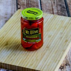 a jar of pickles sitting on top of a wooden cutting board