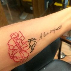 a person with a tattoo on their arm that says, a love song and flowers