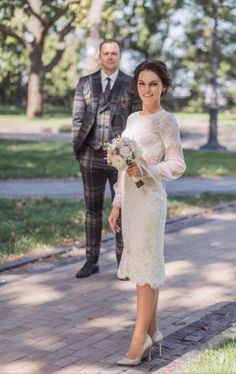 a bride and groom are walking down the sidewalk in their wedding day attire, dressed in plaid suits