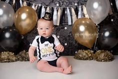 a baby is sitting in front of some balloons