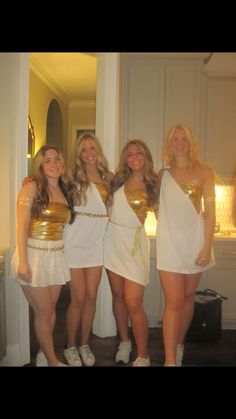 four beautiful women dressed in white posing for a photo with gold decorations on their chests