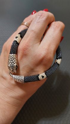 a woman's hand wearing a black and gold snake bracelet