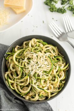 zucchini noodles with parmesan cheese and herbs in a skillet on a white table