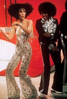 two women in disco outfits standing next to each other