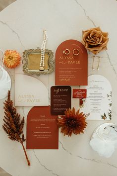 the wedding stationery is laid out on a marble table with flowers and other items