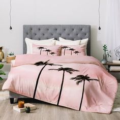 a bed with pink comforter and palm trees on the covers in a bedroom setting