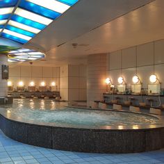 a large indoor swimming pool with lights on the ceiling and tiled flooring around it