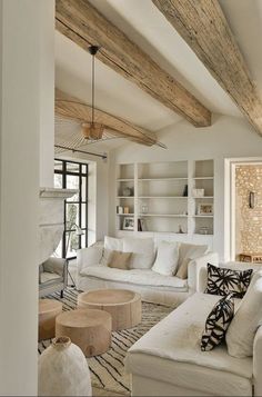 a living room filled with white furniture and wooden beamed ceiling beams in an open floor plan