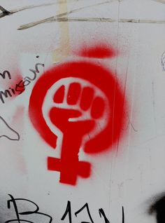 graffiti written on the side of a wall with a red symbol in the foreground