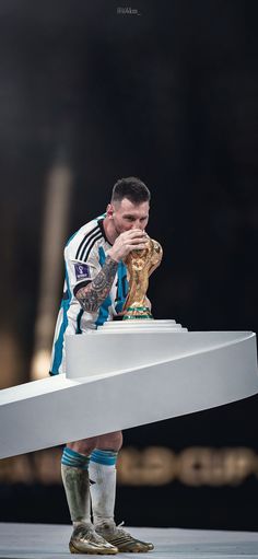 a man holding a soccer ball on top of a white object