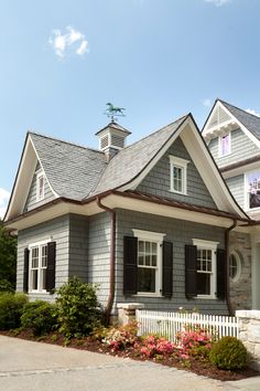 a gray house with white trim and black shutters on the front door is featured in an instagram