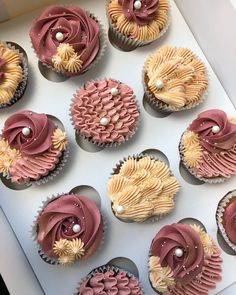 twelve cupcakes with pink and yellow frosting in a box