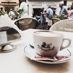 a cup of coffee sitting on top of a white saucer next to a plate