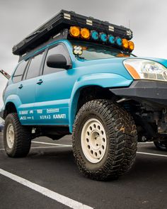 a blue four - doored vehicle parked in a parking lot with its lights on