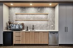 a modern kitchen with stainless steel appliances and wood cabinetry, along with marble walls