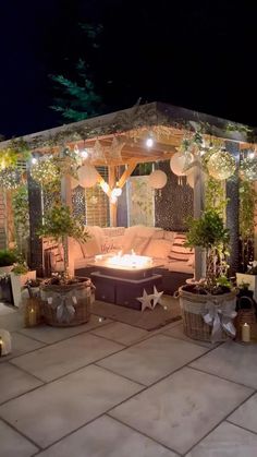 a gazebo decorated with lights and potted plants in the middle of a patio