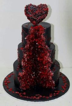 a three tiered cake with red and black decorations on the top, topped with a heart - shaped frosting