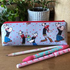 "Cute pencil case handmade from a cotton fabric featuring Popeye the Sailor Man and Olive Oyl. It will make a great gift for your favourite friend or just a treat for yourself!!  It is lined with a red and white polka dot cotton fabric and also reinforced with stabilising foam for structure and protection. It fastens with a top red zip. SIZE: 23cm wide x 8.5cm tall x 7cm depth (9\" x 3.25\" x 2.75) Happy customers said this:  Really happy with this. Such a beautifully made and looking bag. Thank Rectangular Cotton Pencil Case As A Gift, Rectangular Cotton Pencil Case As Gift, Cotton Pencil Case With Pen Holders As Gift, Red Pencil Case With Zipper Pouch As Gift, Cotton Pencil Case With Pen Holders For Personal Use, Red Zipper Pouch Pencil Case As Gift, Classic Pencil Case With Pen Holders As Gift, Cotton Pencil Case With Zipper Pouch, Popeye And Olive Tattoo