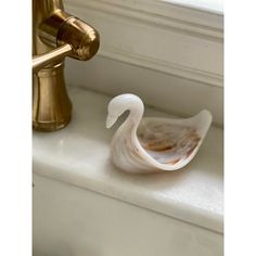 a swan figurine sitting on the edge of a sink