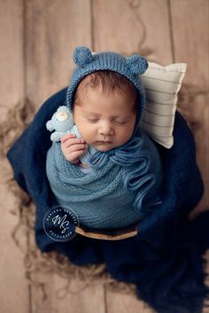 a baby wrapped in blue is holding a stuffed animal