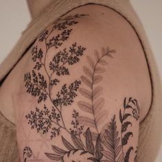 a woman's arm with tattoos on it and some plants growing out of it