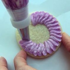 someone is decorating a cookie with purple icing