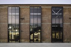 three windows on the side of a brick building with black frames and glass doors in front of them