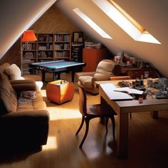 an attic living room with couches, chairs and a pool table in the corner