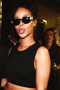 a woman sticking out her tongue while wearing sunglasses